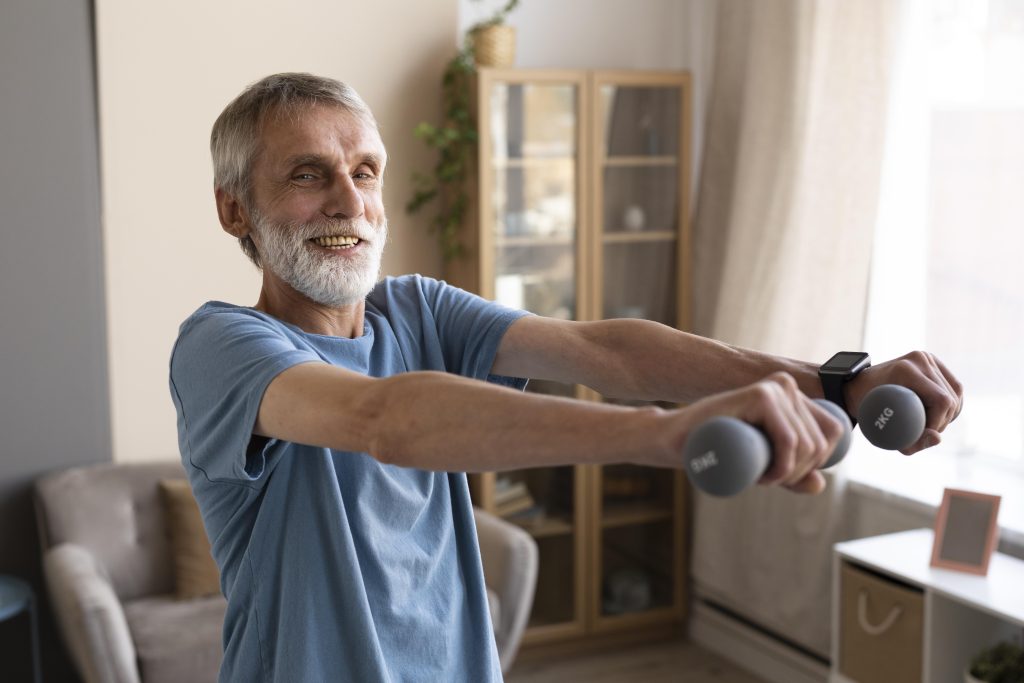 älterer Mann trainiert mit Hanteln zu Hause